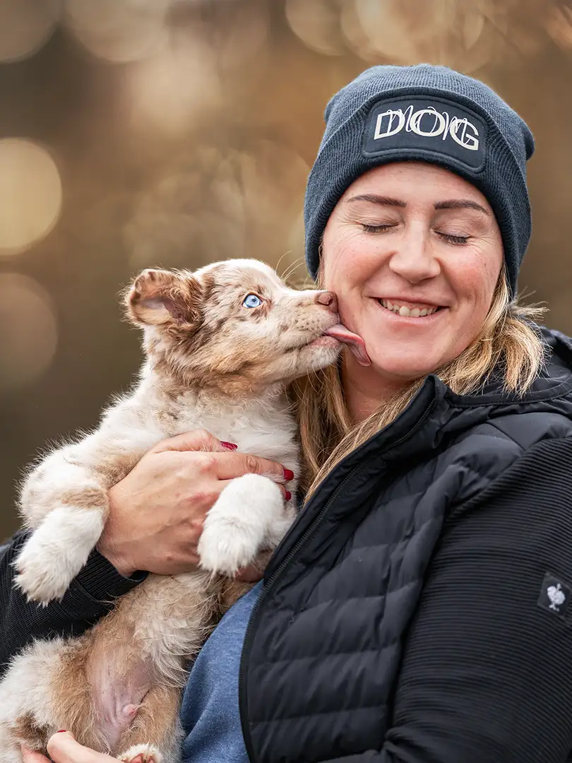 Hundewelpe leckt einer Frau durch das Gesicht